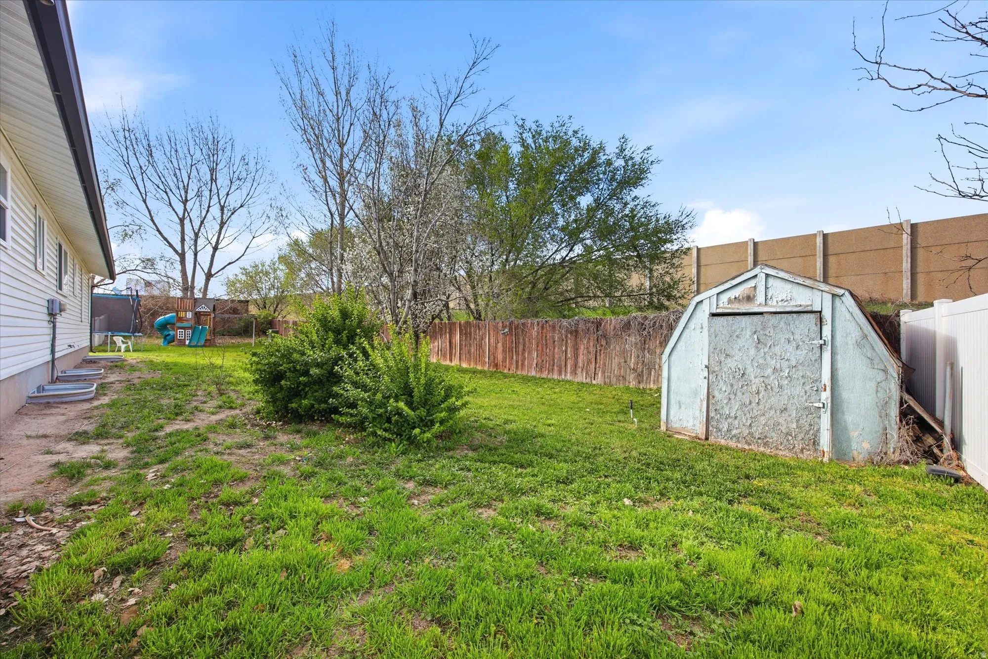 Fenced backyard featuring a storage unit
