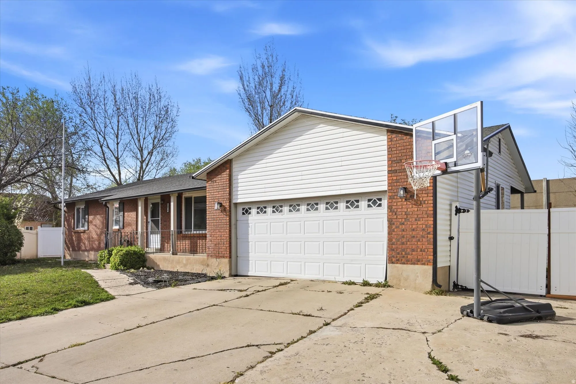 View of front of house featuring brick siding, driveway, a garage, and covered porch