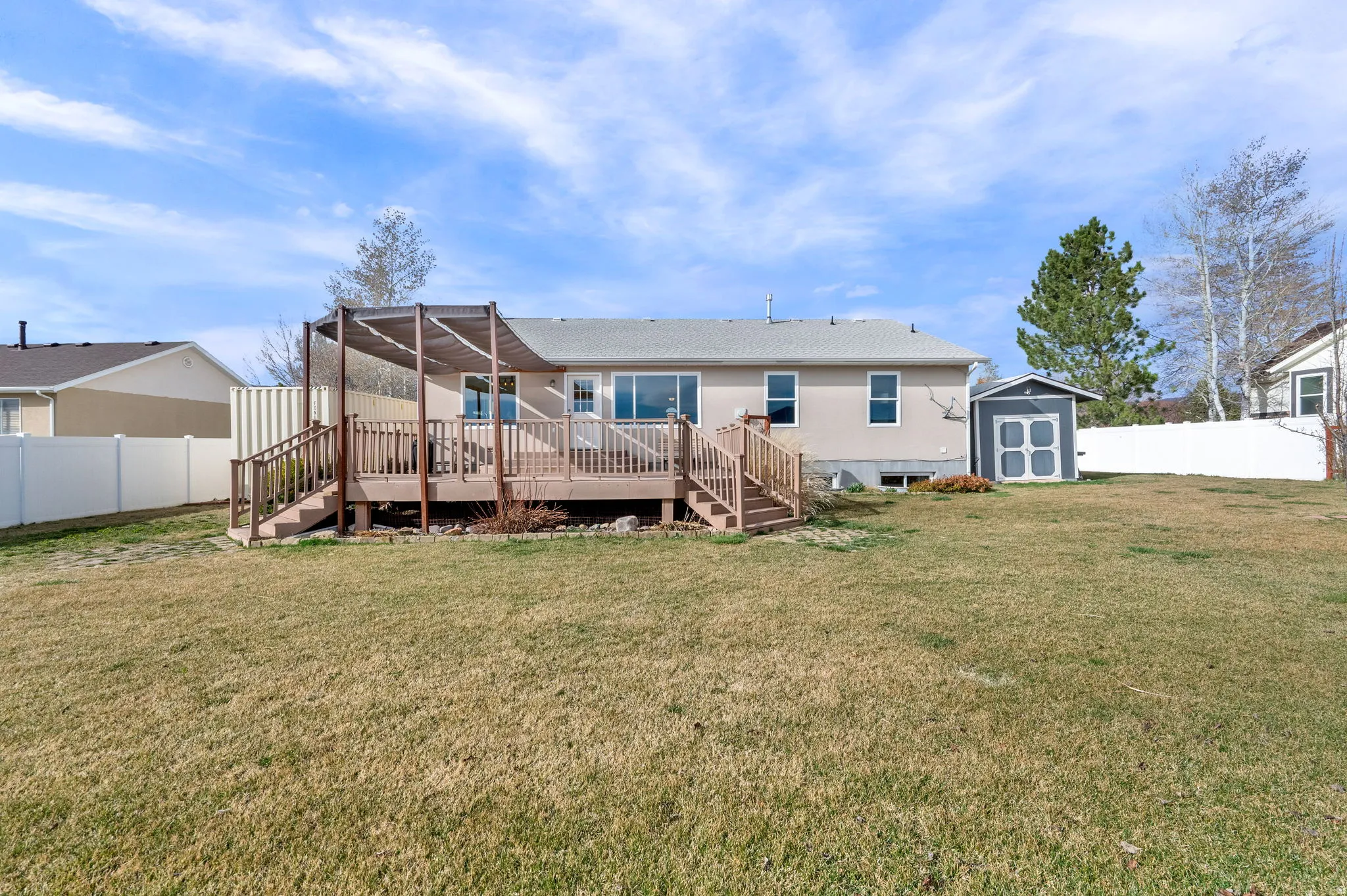 Back of house with a storage shed, a fenced backyard, and a deck