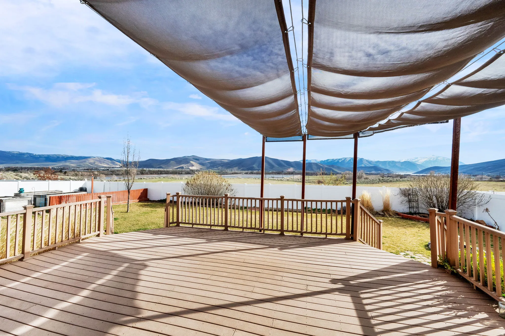Faux wooden deck with a fenced backyard and a water and mountain view