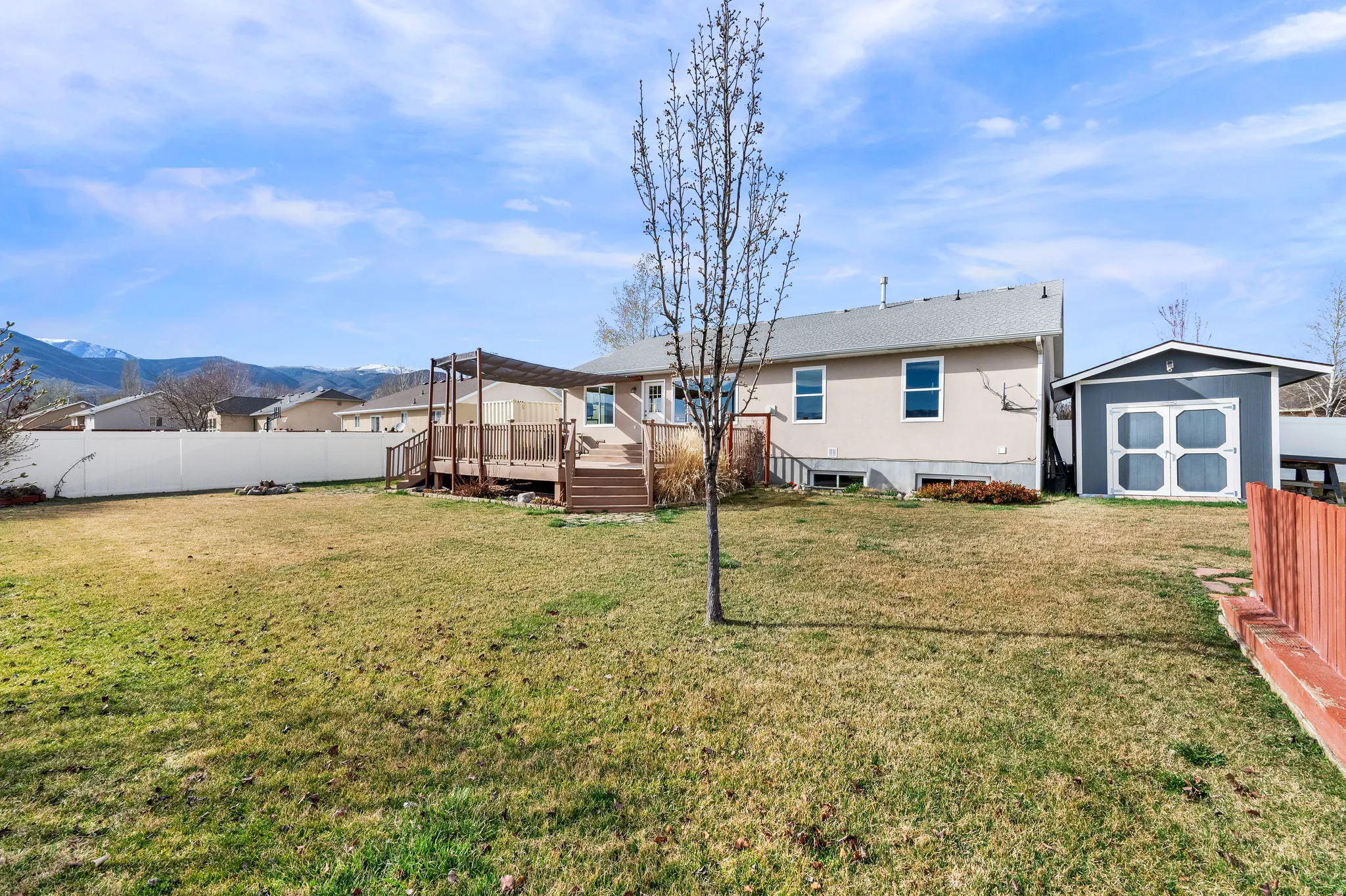 Back of property featuring a shed, a fenced backyard, and a faux wooden deck