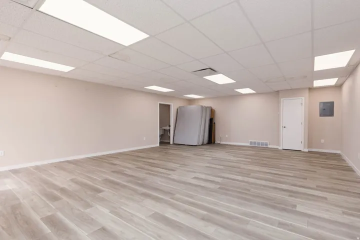 Unfurnished room featuring light wood finished floors, a paneled ceiling, and electric panel