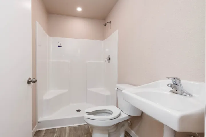 Full bathroom featuring a stall shower, a textured wall, and wood finished floors