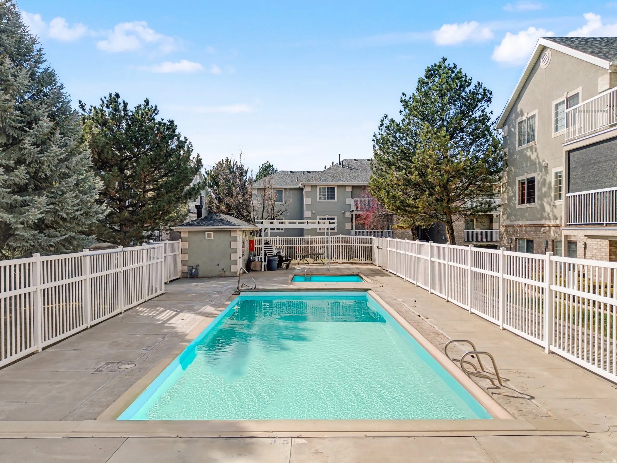 Community pool with a fenced backyard, a patio area, and a residential view