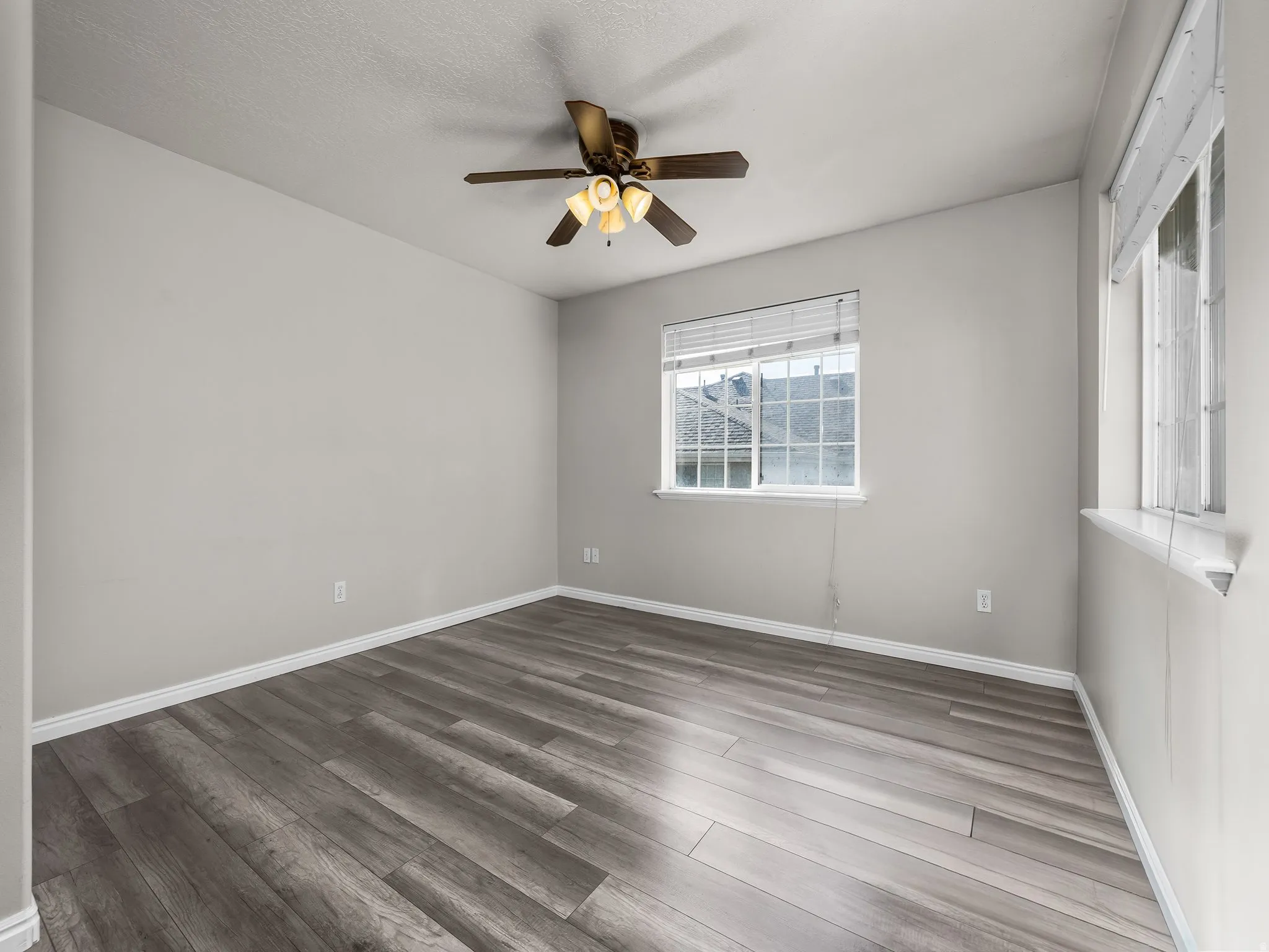 Spare room with dark wood finished floors, a ceiling fan, and a textured ceiling