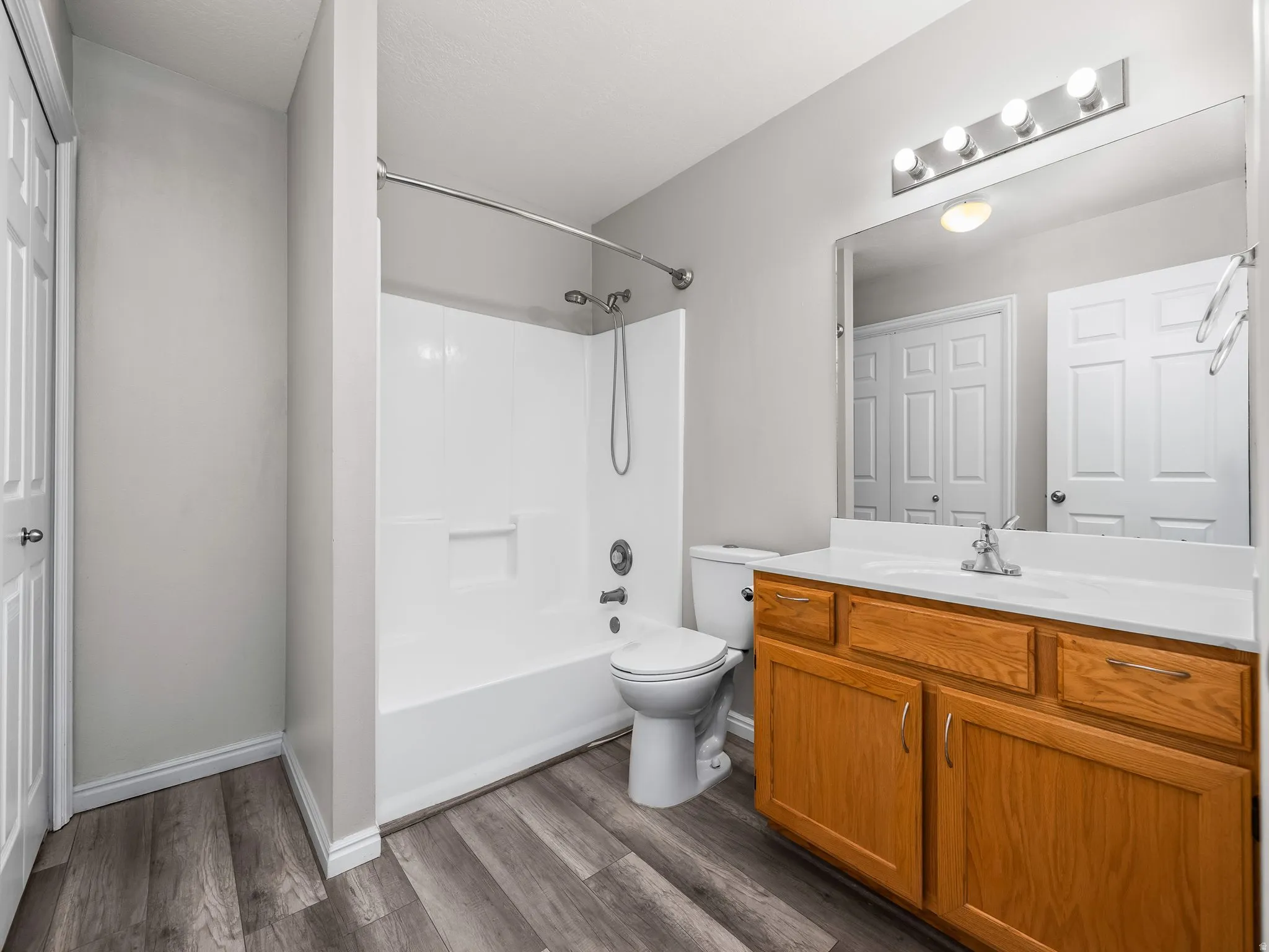 Full bathroom with vanity, shower / bath combination, and dark wood-style flooring