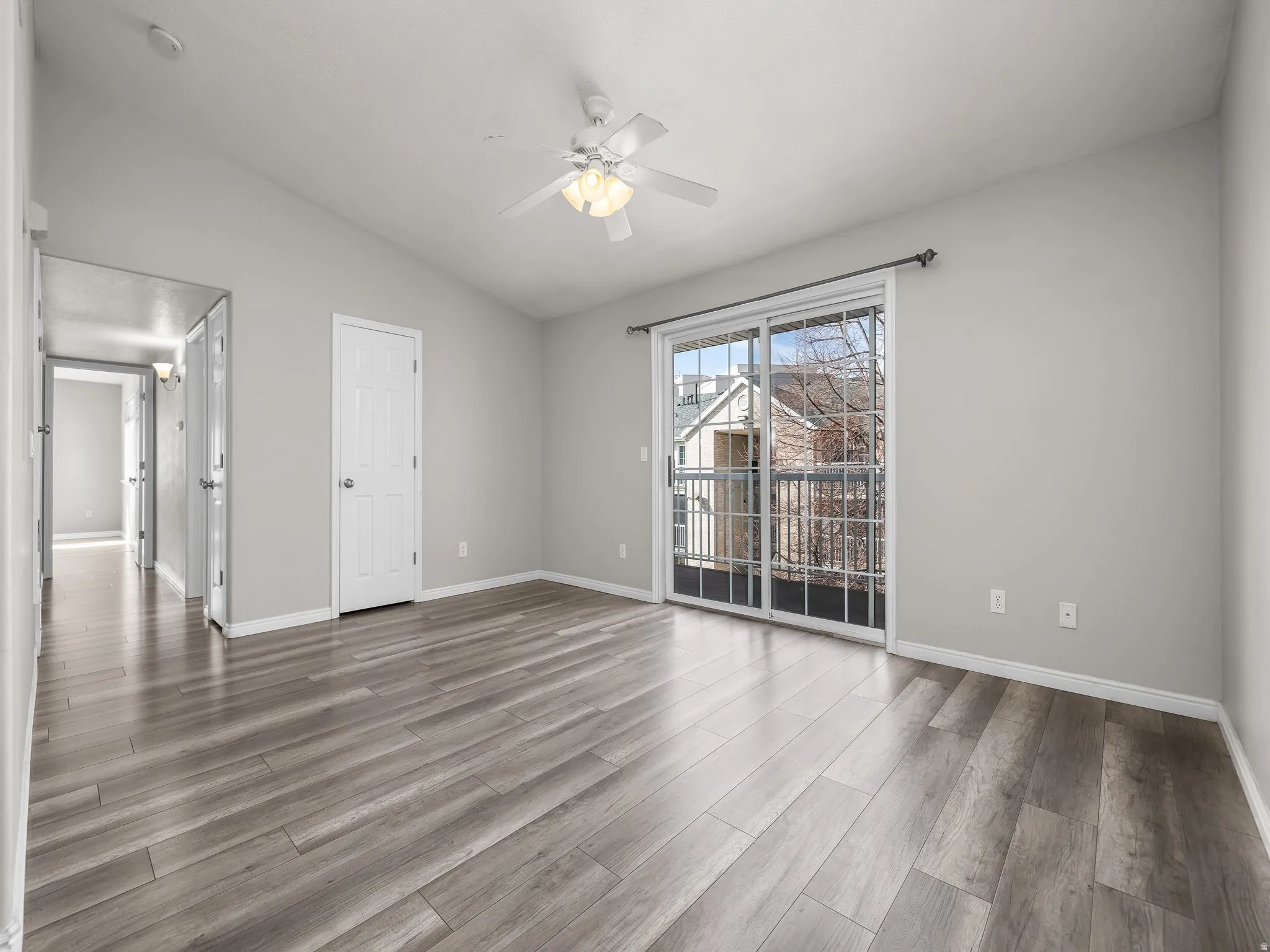 Spare room with a ceiling fan, lofted ceiling, and light wood-style flooring