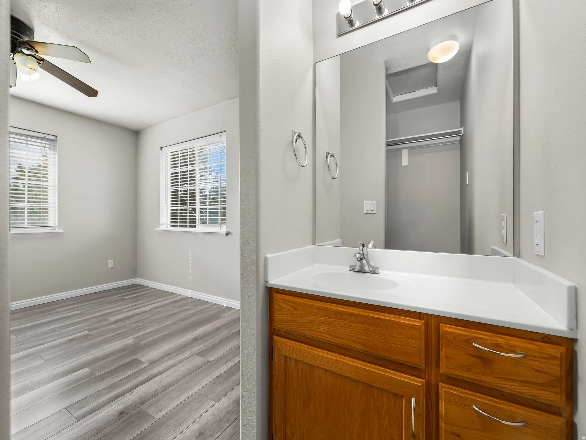 Bathroom with vanity, a textured ceiling, wood finished floors, and ceiling fan