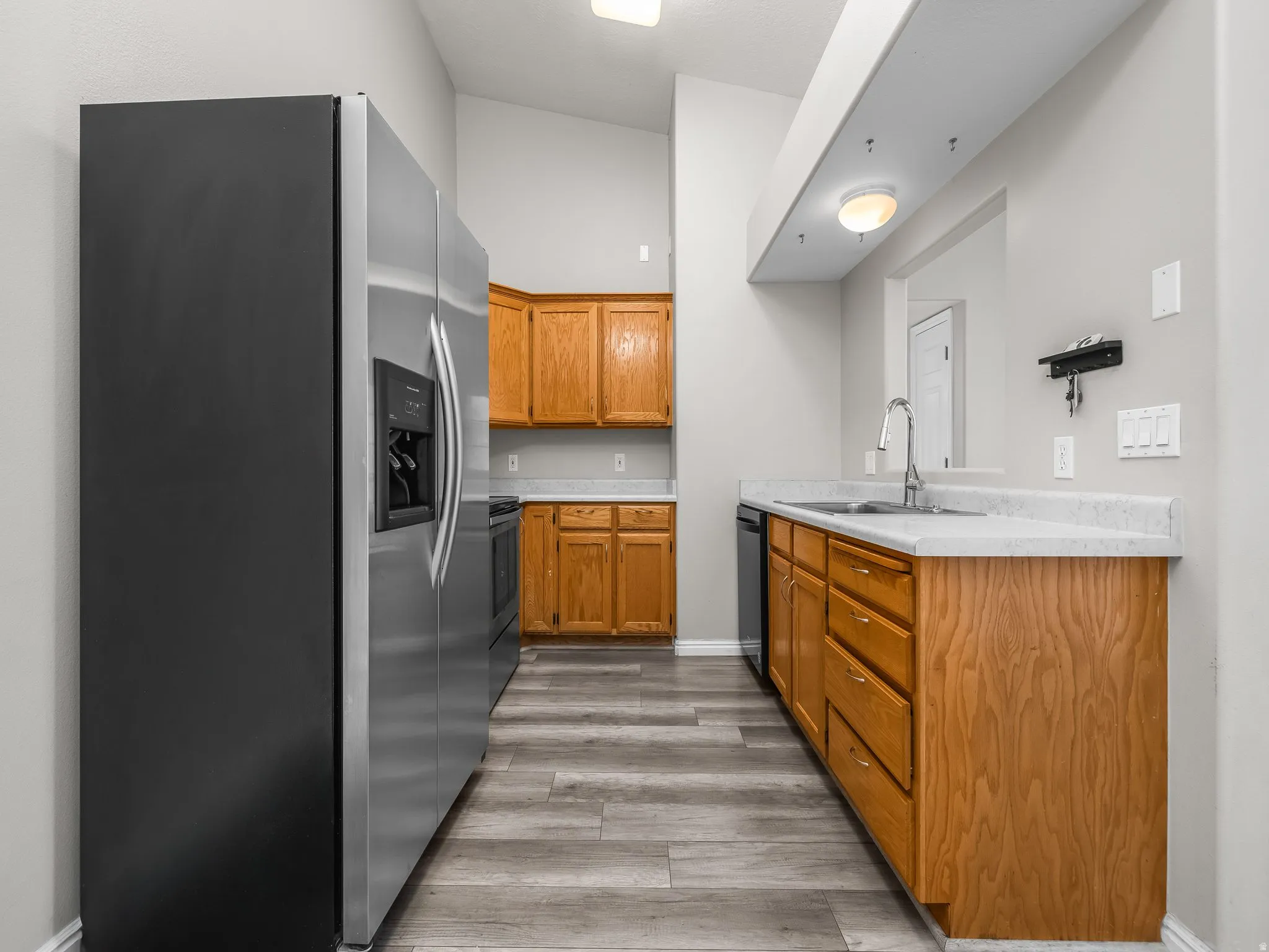 Kitchen with stainless steel appliances, light countertops, wood finish cabinetry, and light wood finished floors