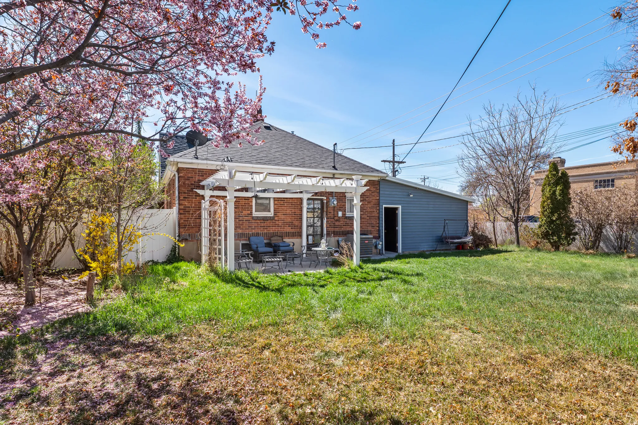 Back of house featuring a pergola, a patio area, roof with shingles, brick siding, and a fenced backyard