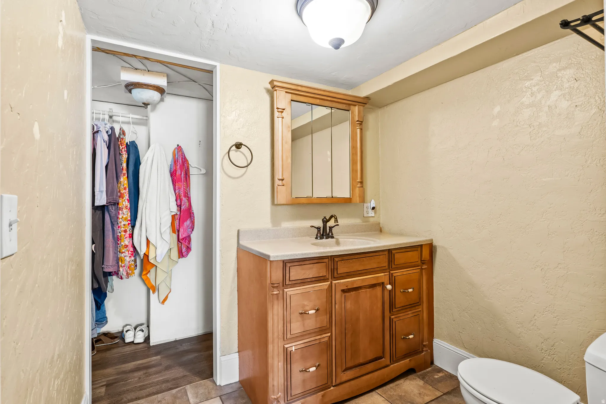 Bathroom with a textured wall, vanity, and a walk in closet
