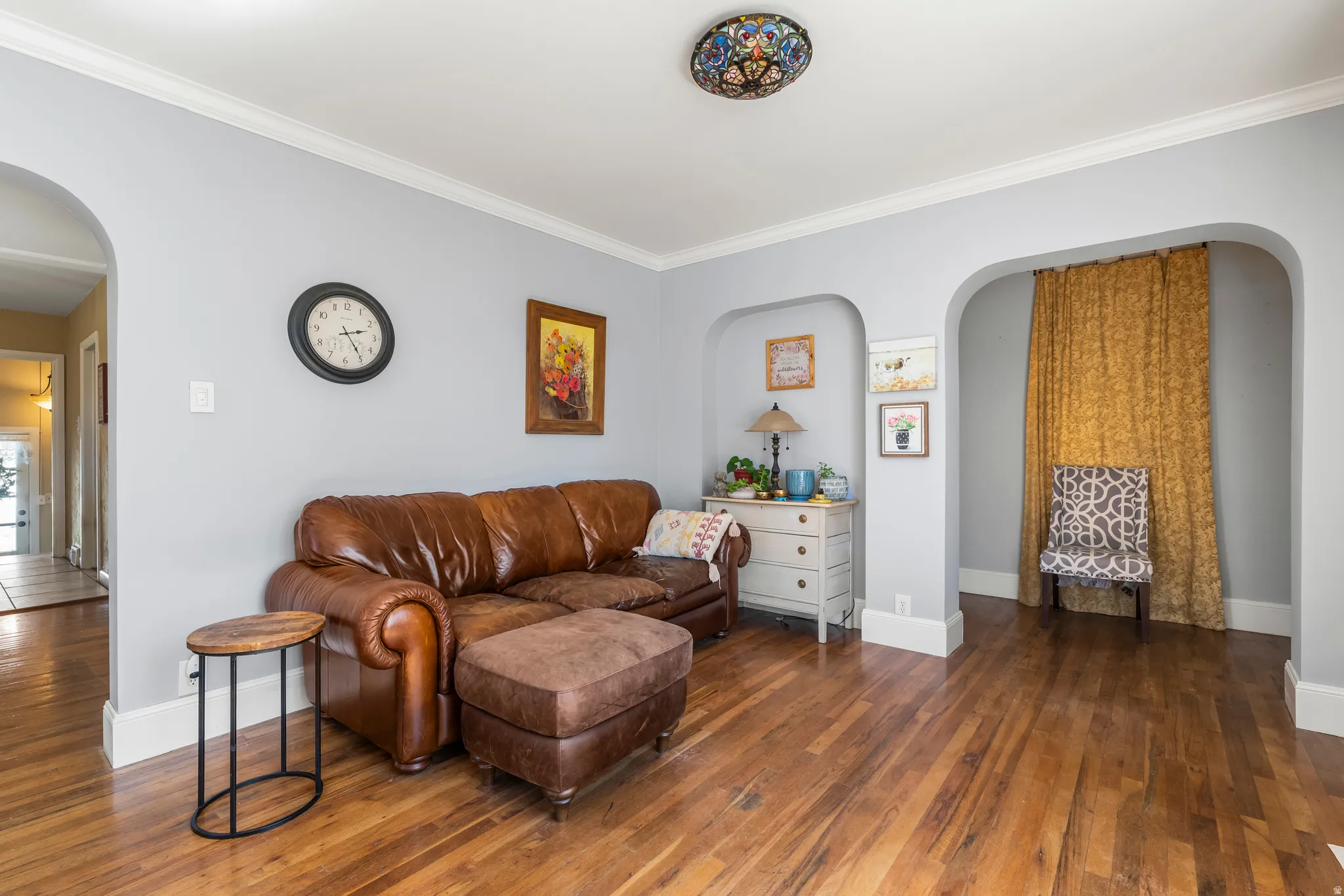 Sitting room featuring arched walkways, dark wood-style flooring, and ornamental molding