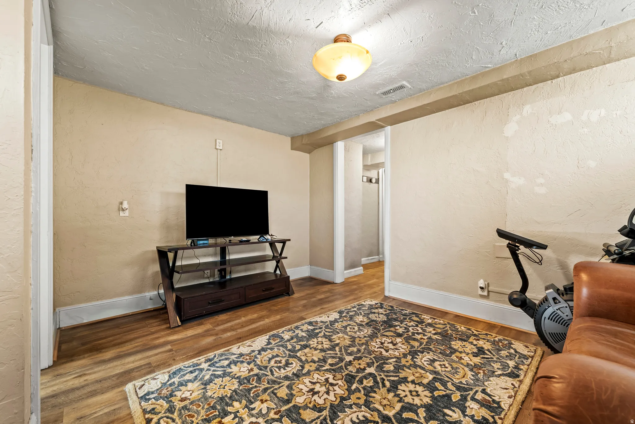 Living area with a textured wall, wood finished floors, and a textured ceiling
