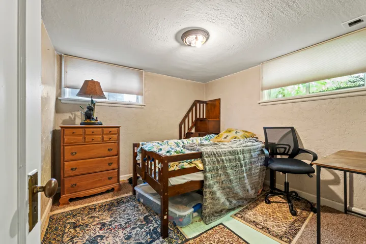 Bedroom featuring a textured wall, a textured ceiling, and multiple windows