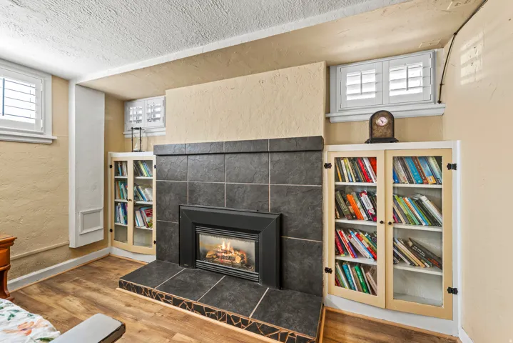 Detailed view of a textured wall, a fireplace, wood finished floors, and a textured ceiling