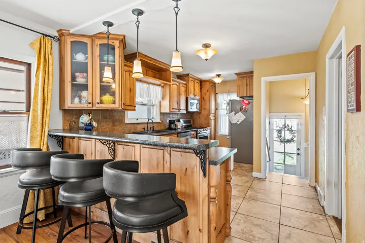 Kitchen featuring a breakfast bar area, stainless steel appliances, dark countertops, decorative backsplash, and a peninsula