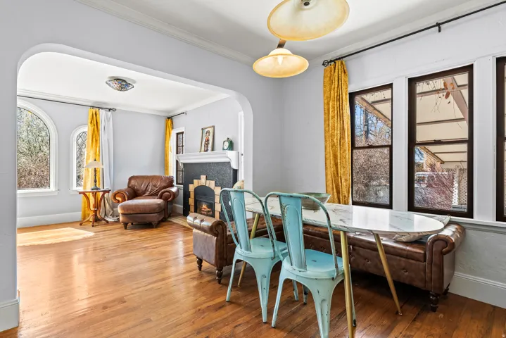 Dining space featuring arched walkways, a fireplace, crown molding, and hardwood / wood-style flooring