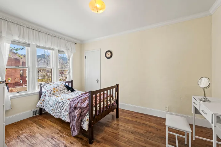 Bedroom with wood-type flooring and crown molding