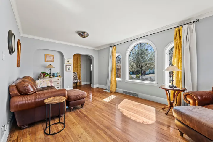 Sitting room featuring crown molding, arched walkways, and wood-type flooring