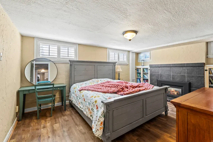 Bedroom with a textured wall, dark wood-style flooring, a textured ceiling, and a fireplace