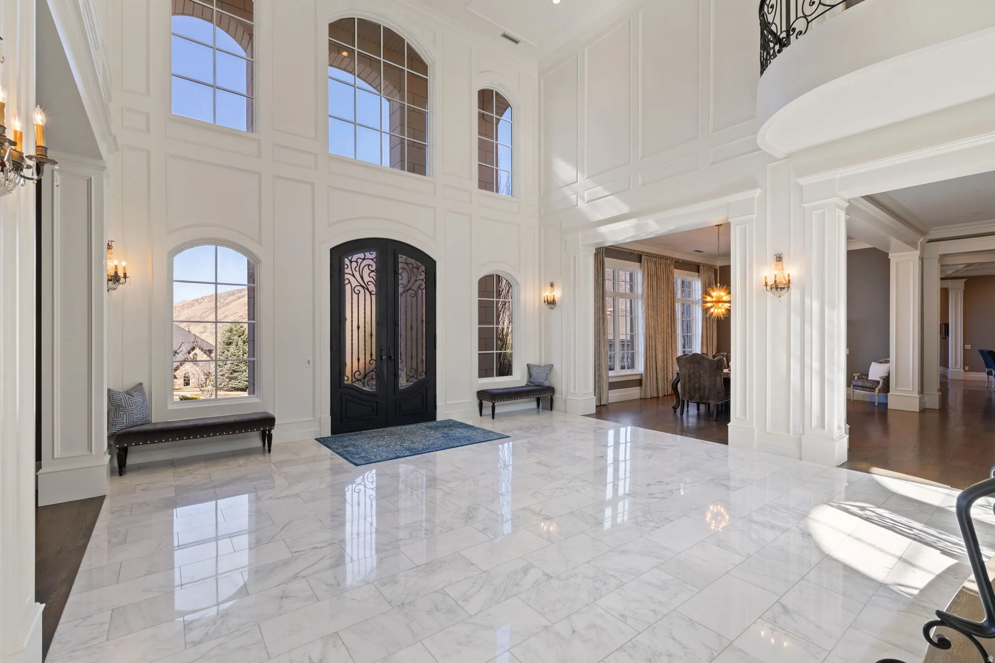 Foyer entrance featuring a decorative wall, a high ceiling, marble tiled floors, french doors, and hanging lights