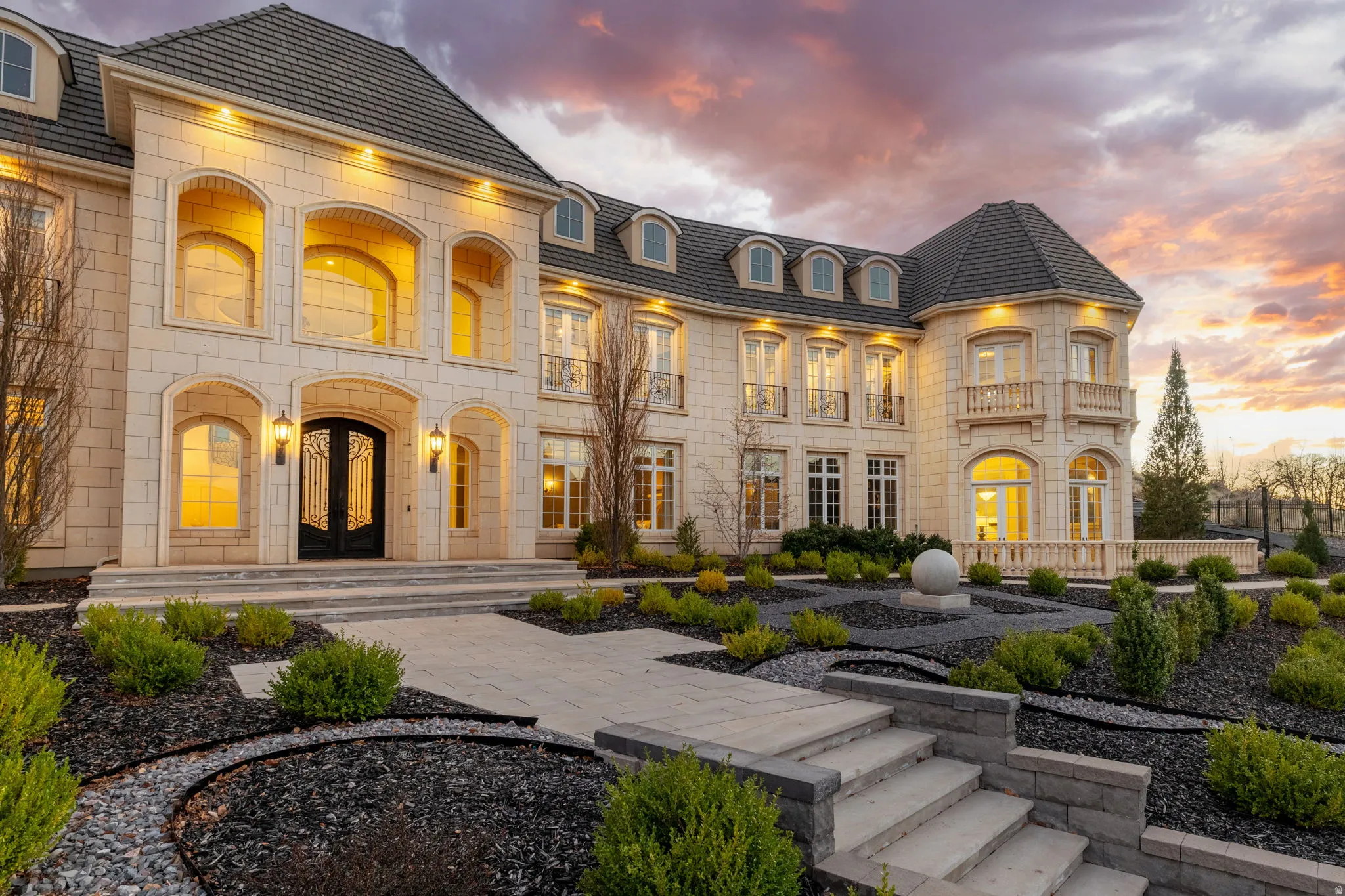 Rear view of house featuring french doors, stone siding, and a balcony