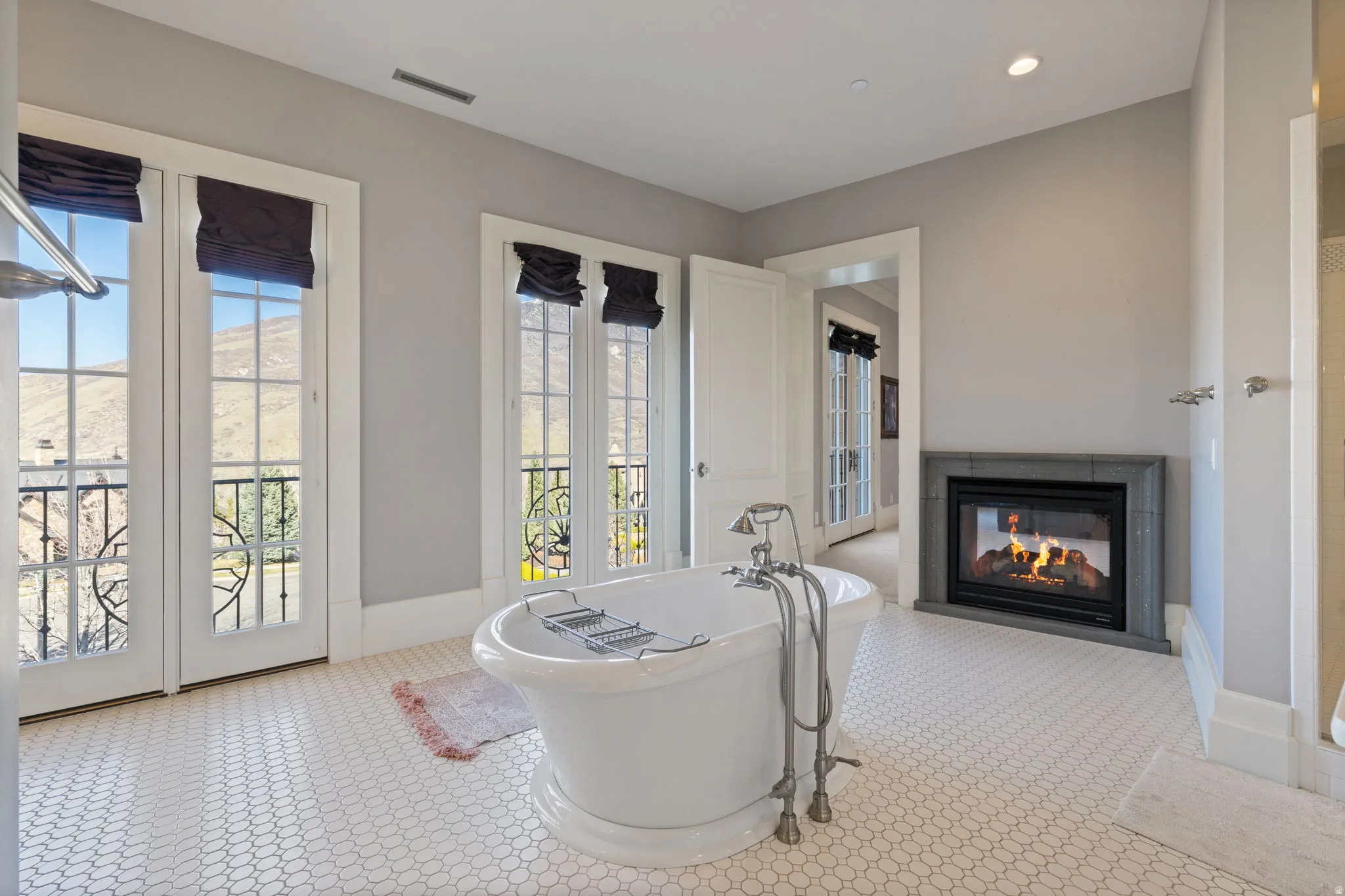 Full bath featuring a freestanding bath, a multi sided fireplace, and recessed lighting