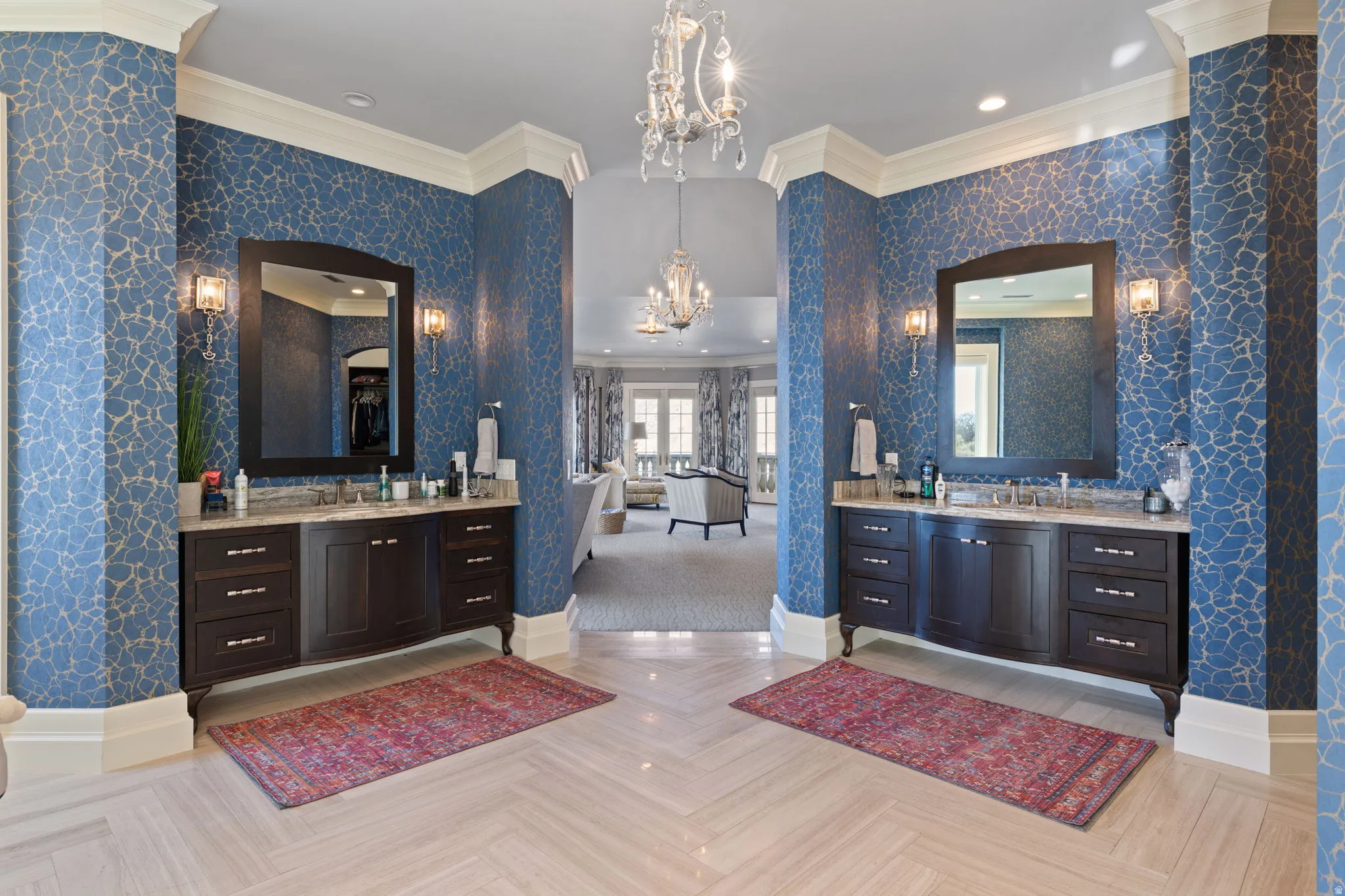 Full bathroom featuring crown molding, hanging lights, wallpapered walls, two vanities, and parquet flooring
