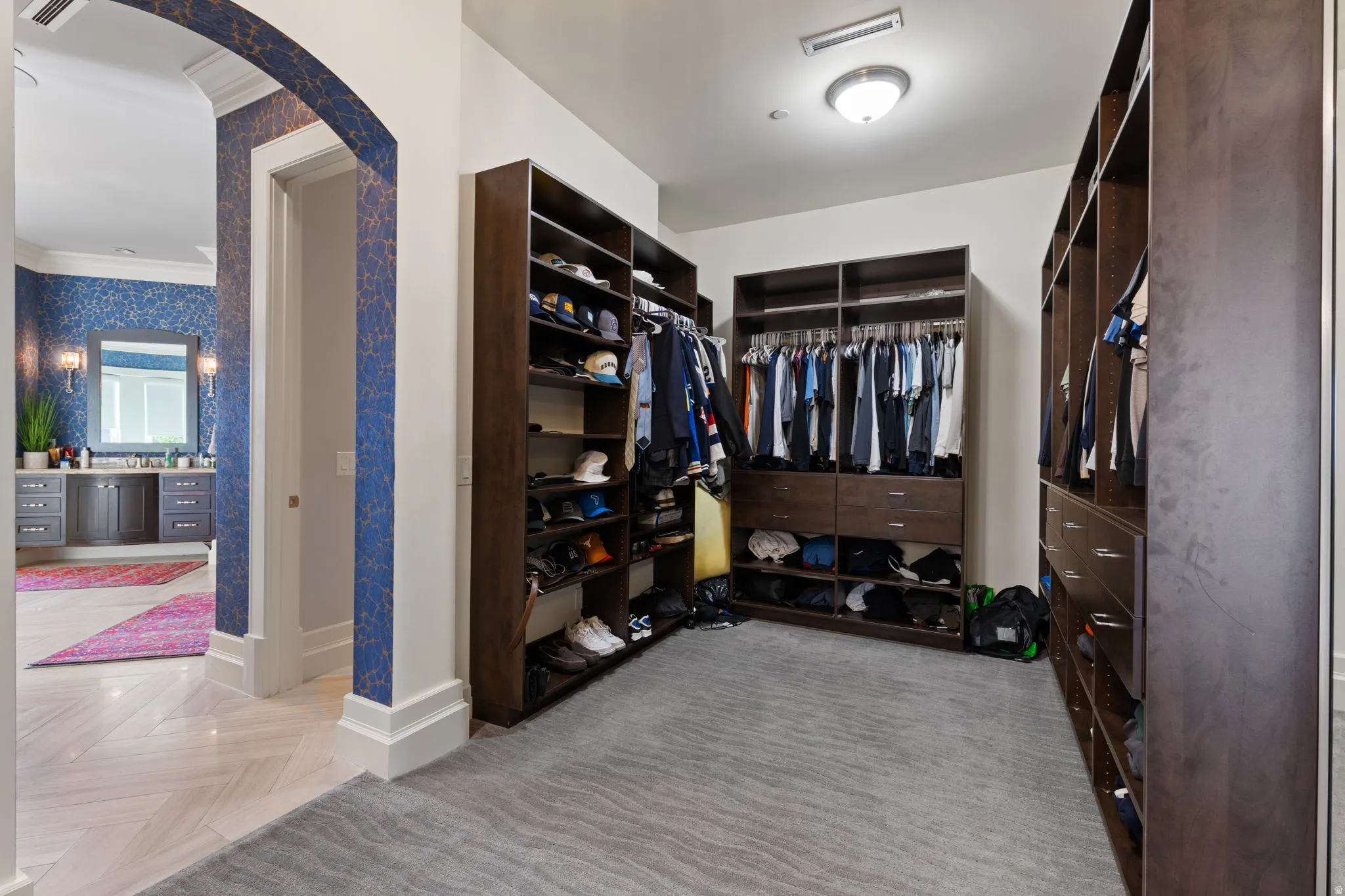 Walk in closet with arched walkways and parquet floors