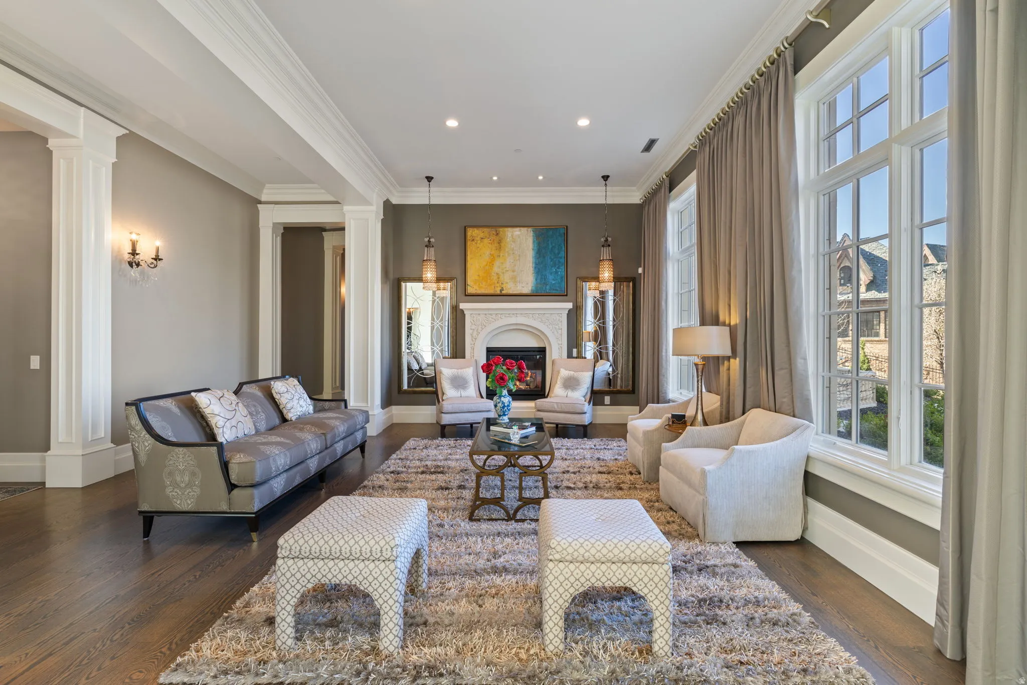 Living room featuring ornate columns, a fireplace, ornamental molding, dark wood finished floors, and recessed lighting