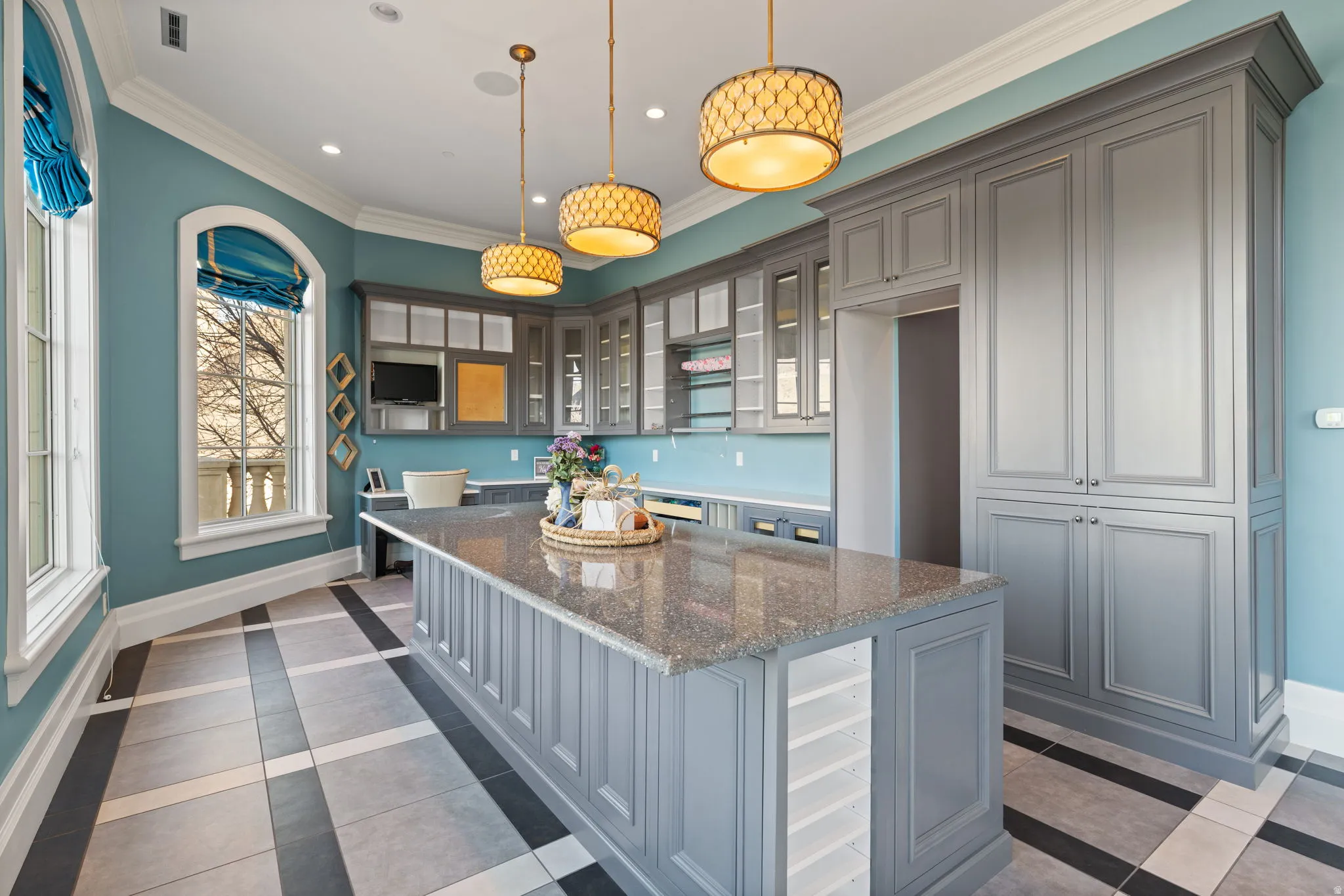 Kitchen featuring gray cabinetry, inlaid floor details, a kitchen island, dark stone counters, and glass insert cabinets