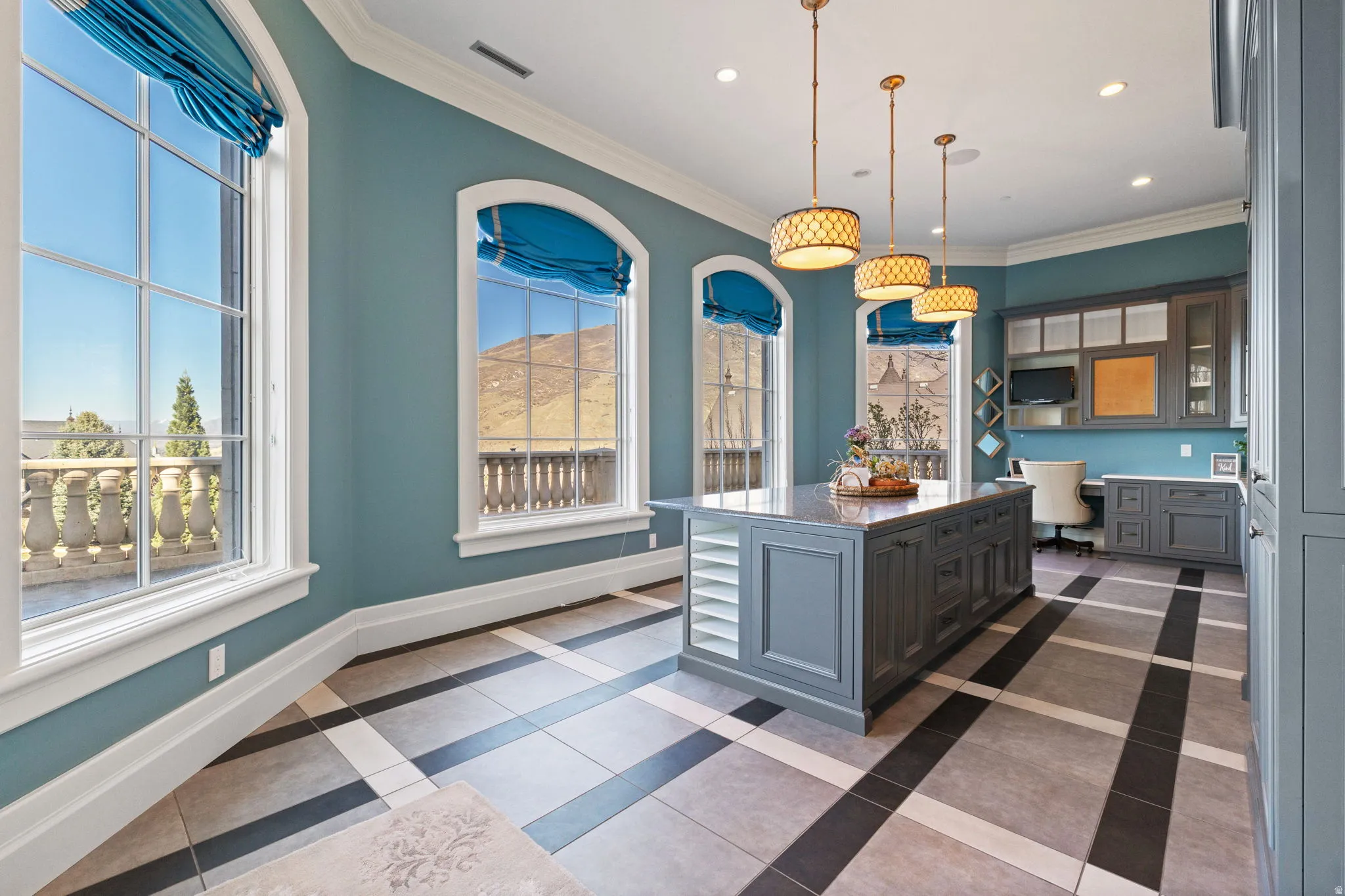 Kitchen featuring hanging light fixtures, light stone countertops, crown molding, glass fronted cabinets, and gray cabinetry