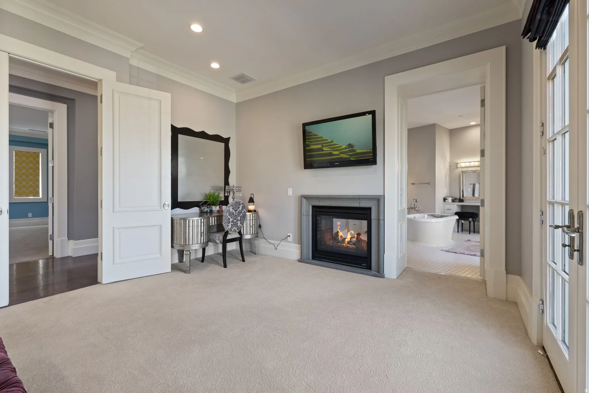 Living area with recessed lighting, ornamental molding, light carpet, and a multi sided fireplace