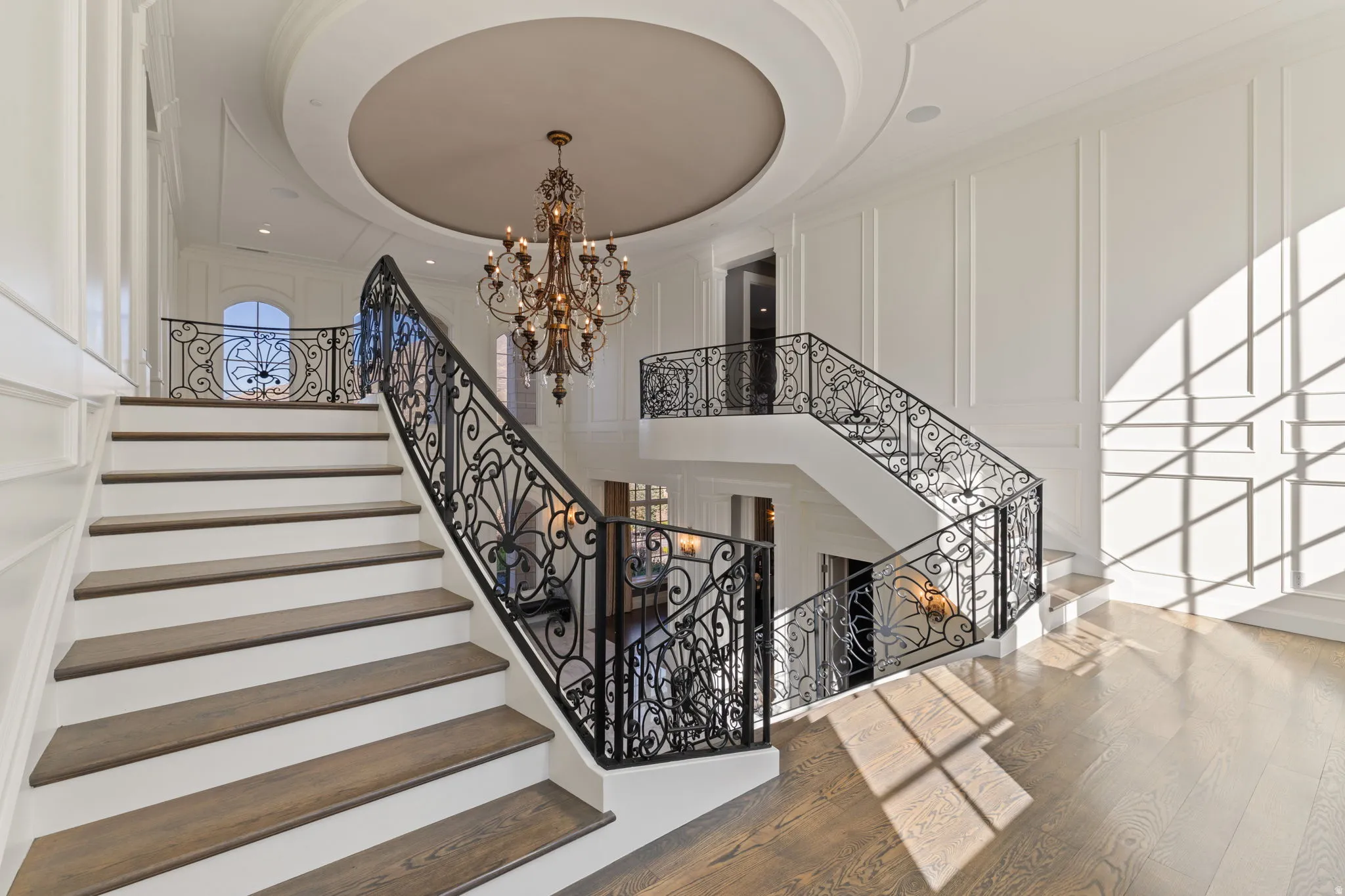 Stairway featuring a chandelier, wood finished floors, a high ceiling, and a decorative wall