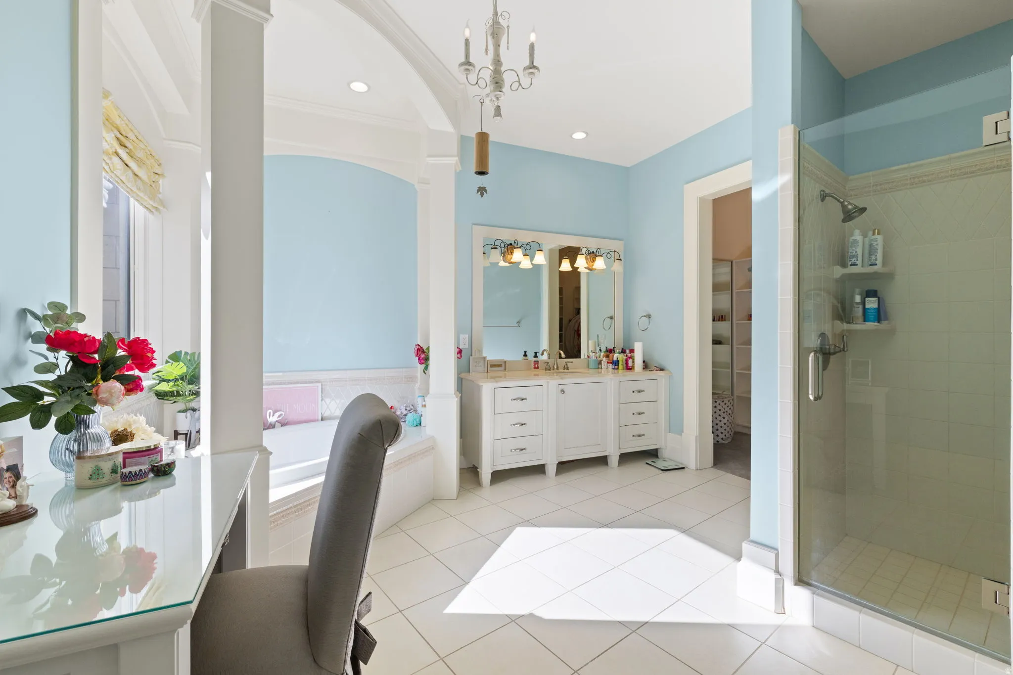 Bathroom featuring a shower stall, light tile patterned floors, vanity, a garden tub, and a walk in closet