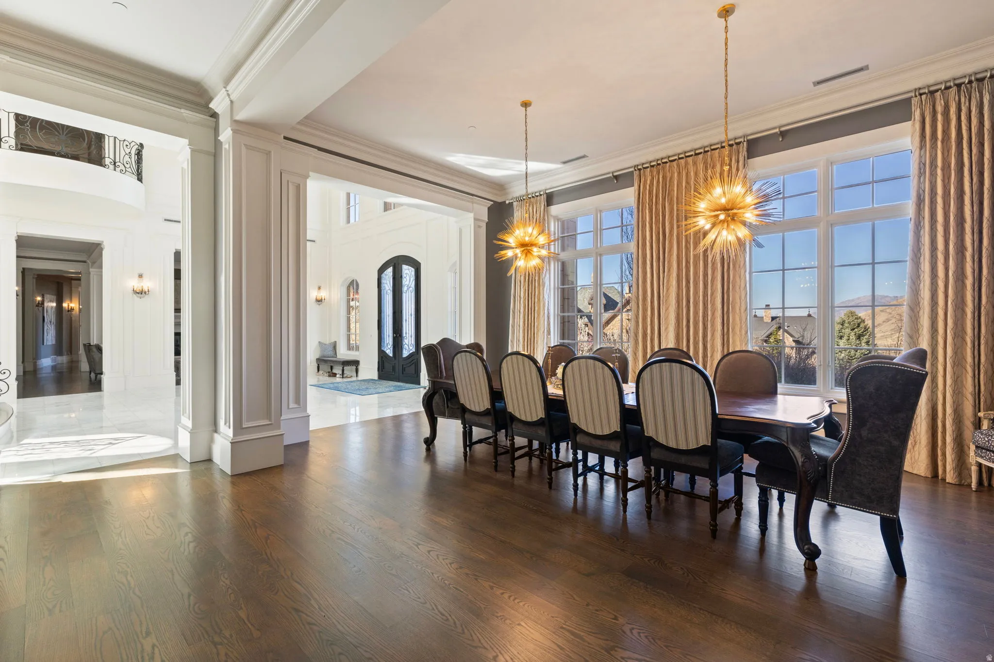 Dining area with dark wood finished floors, crown molding, a chandelier, healthy amount of natural light, and arched walkways