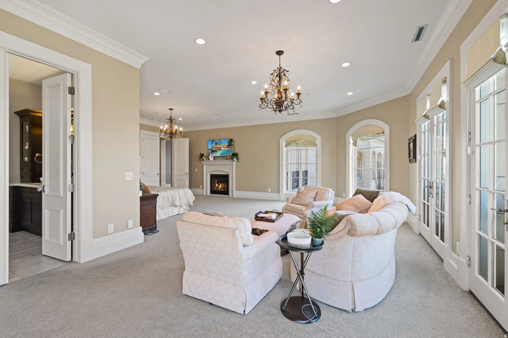 Living room featuring a lit fireplace, crown molding, suspended lighting, and light colored carpet