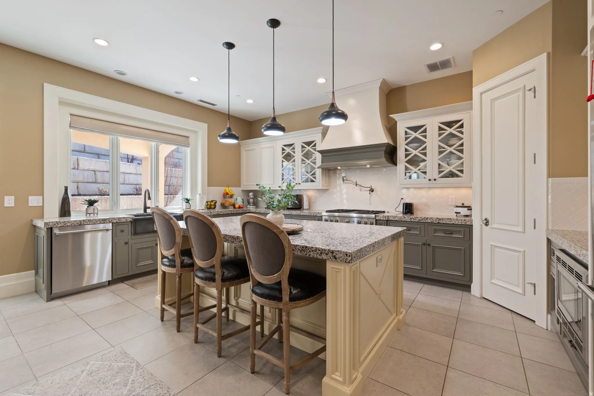 Kitchen featuring dishwasher, a breakfast bar, pendant lighting, and light tile patterned floors