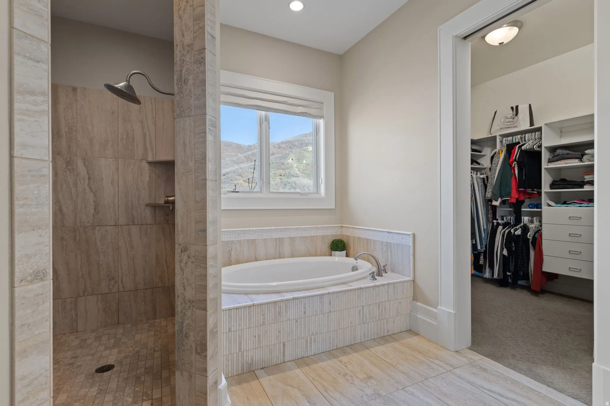 Full bathroom with a bath, walk in shower, a walk in closet, and light colored carpet