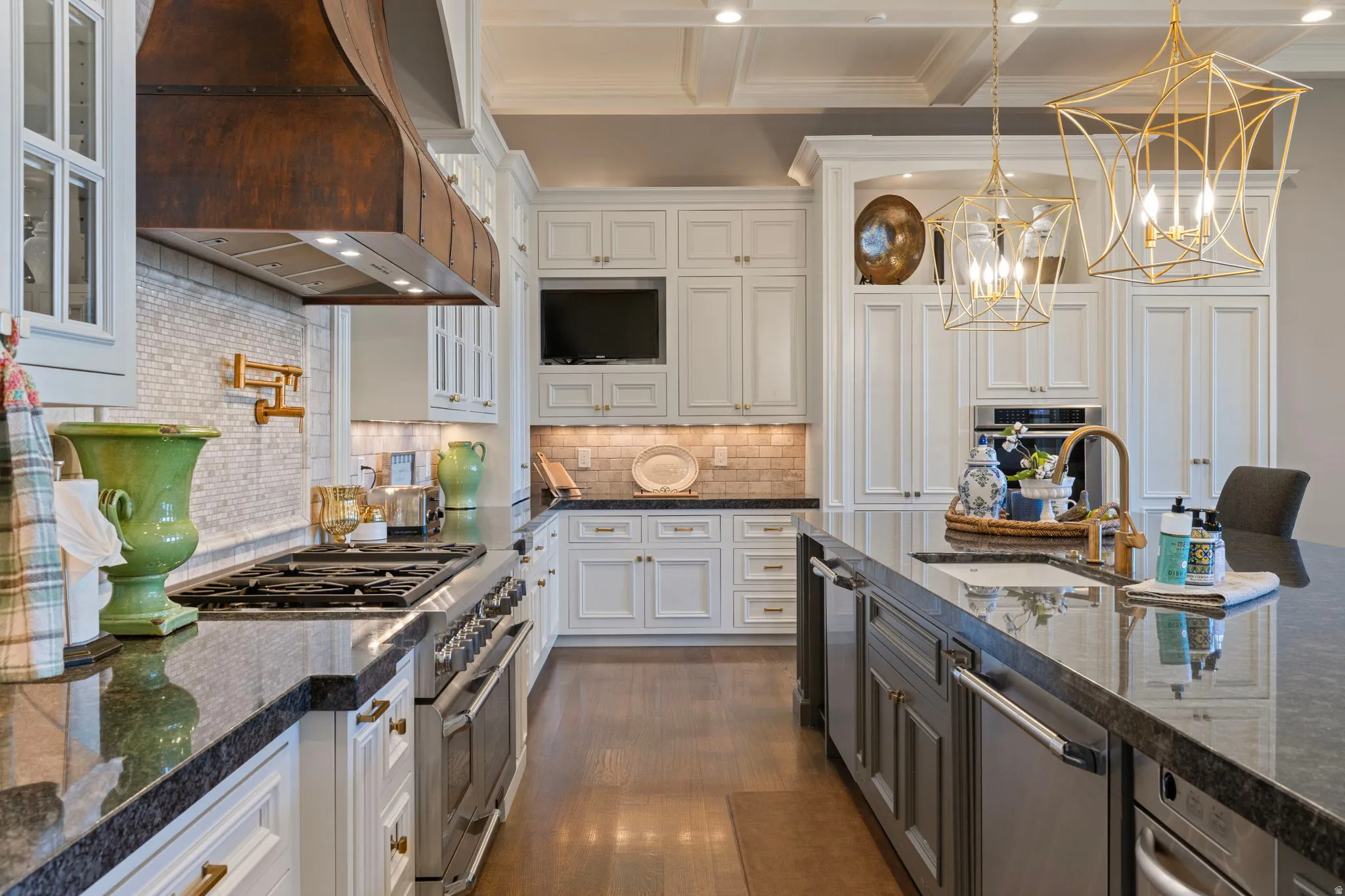 Kitchen with stainless steel appliances, dual tone cabinetry, hanging lights, dark stone countertops, and decorative backsplash