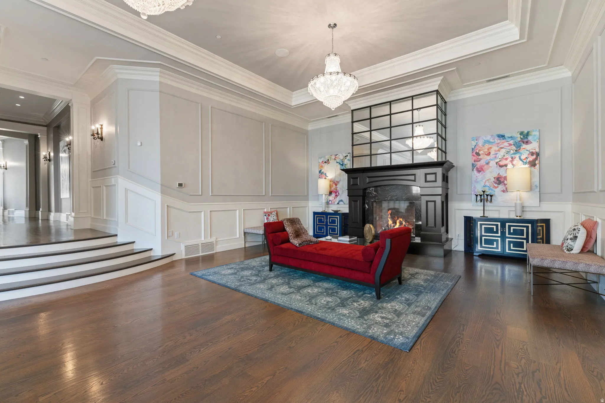 Living room featuring a decorative wall, a chandelier, dark wood-type flooring, a large fireplace, and ornamental molding