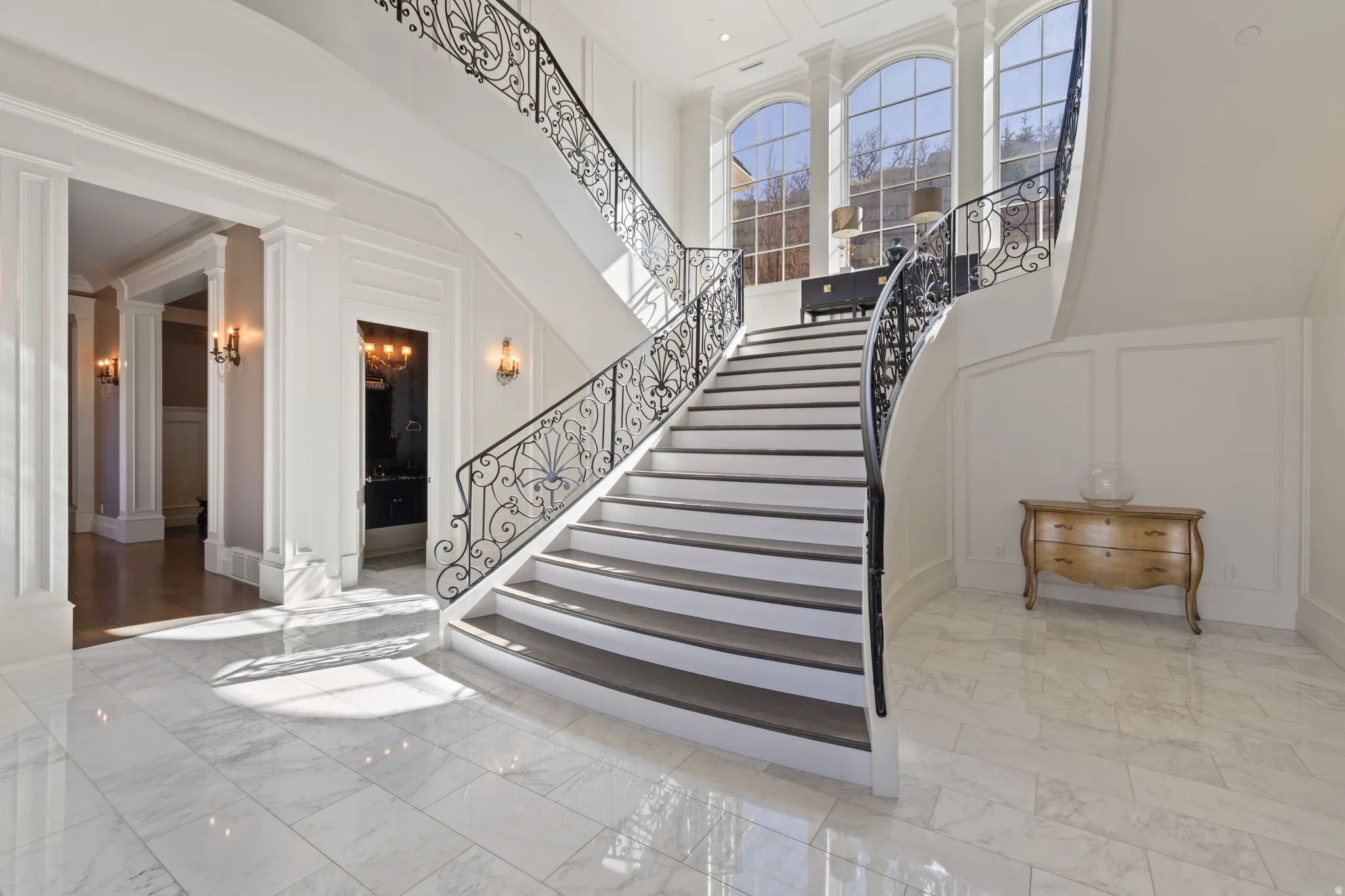 Staircase with a decorative wall, a high ceiling, decorative columns, marble finish floors, and ornamental molding