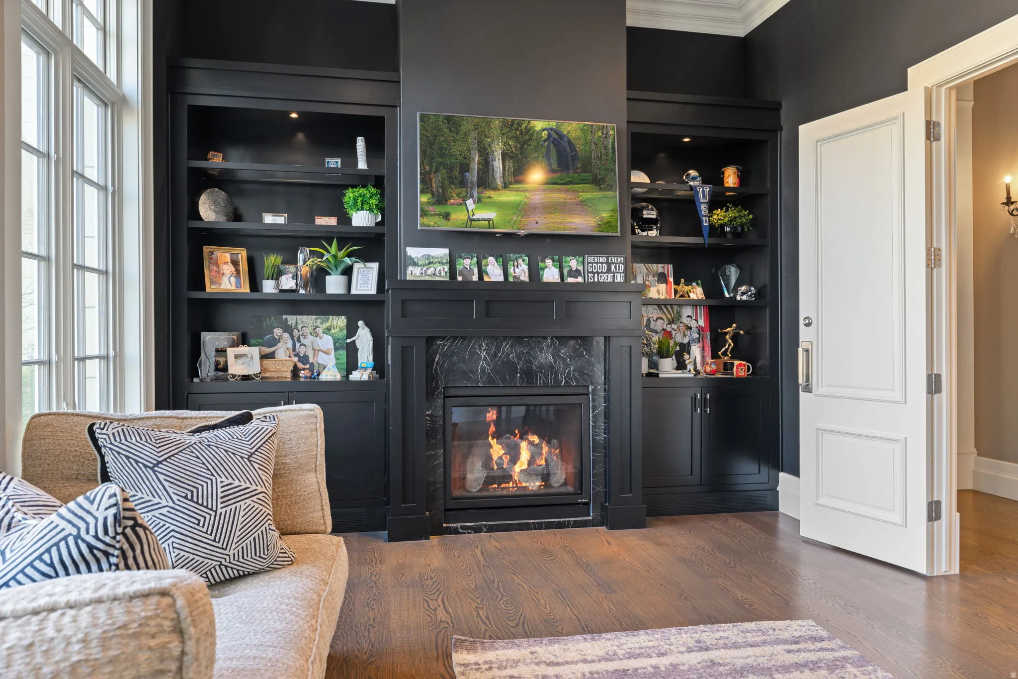 Living area featuring built in shelves, a fireplace, wood finished floors, and ornamental molding