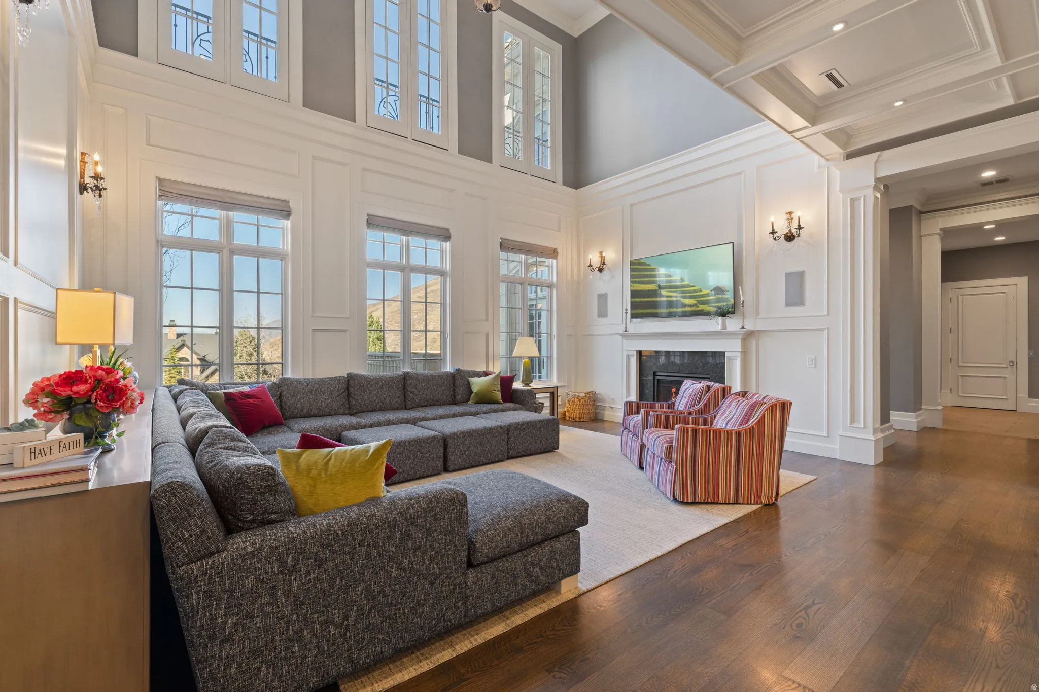 Living area featuring a decorative wall, hardwood / wood-style flooring, a fireplace, a high ceiling, and crown molding