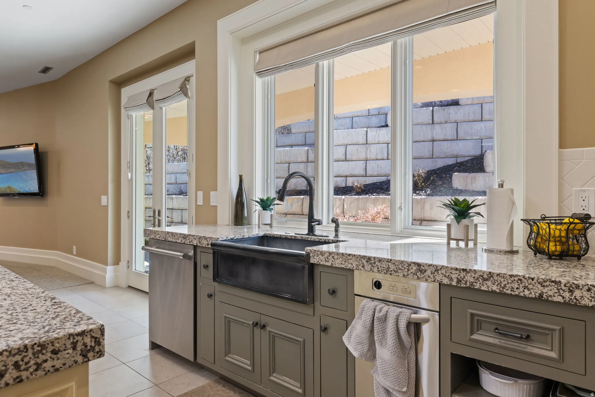 Kitchen with light stone countertops, gray cabinetry, light tile patterned floors, and dishwasher