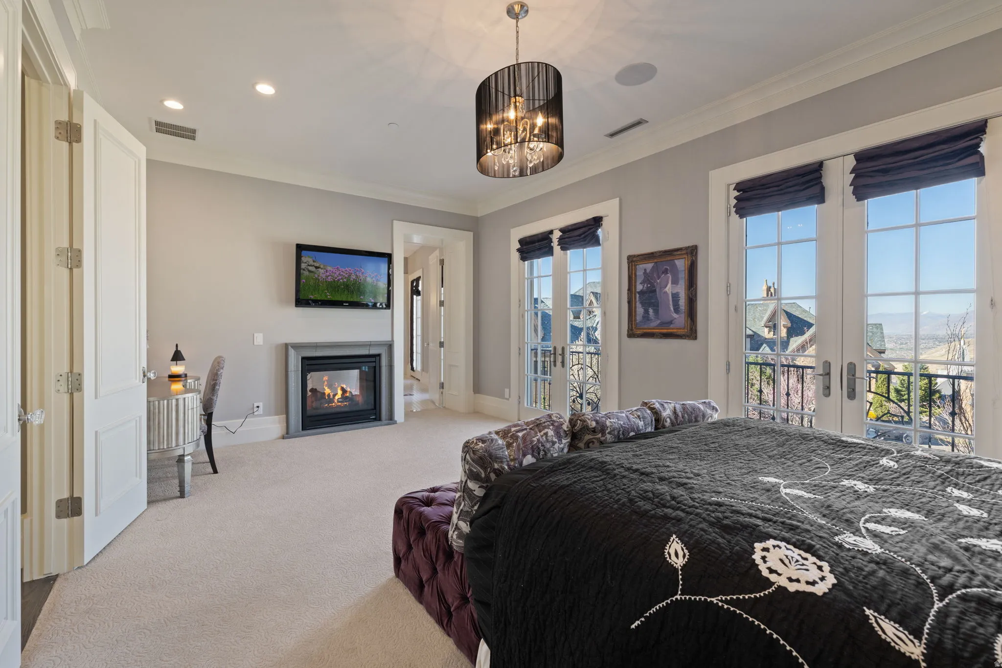 Bedroom with access to outside, ornamental molding, light carpet, a fireplace with flush hearth, and french doors
