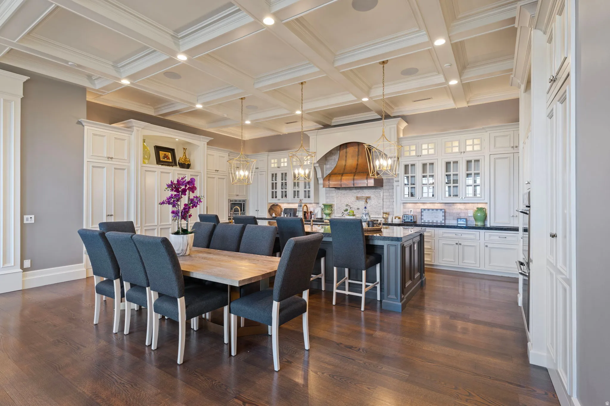 Dining area featuring suspended lighting, dark wood-style floors, coffered ceiling, and ornamental molding