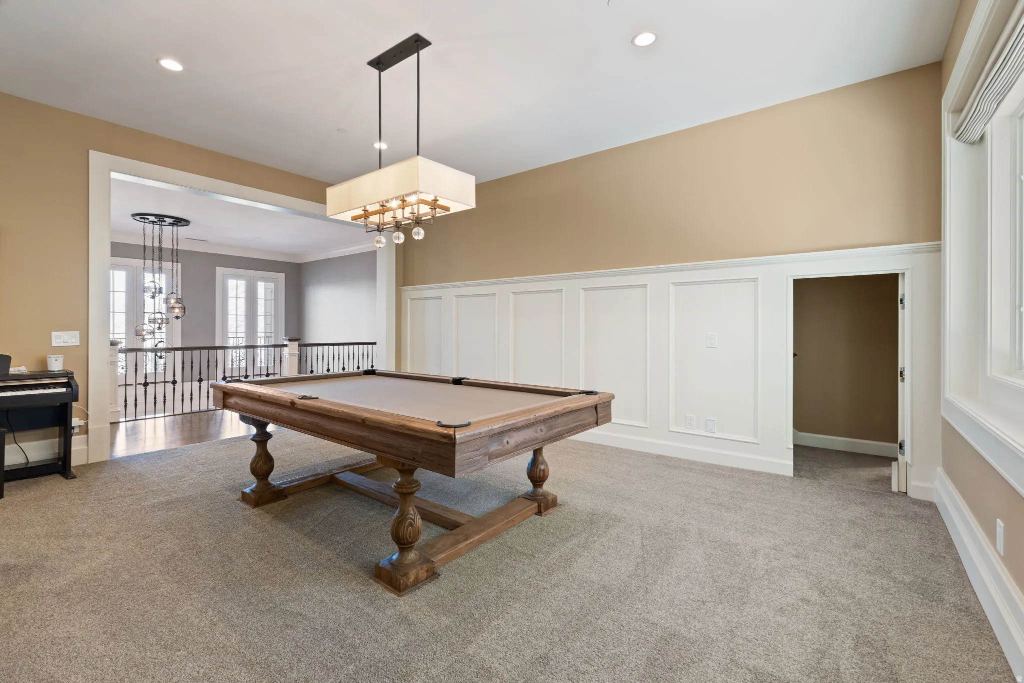 Recreation room featuring a decorative wall, pool table, a wainscoted wall, carpet, and suspended lighting