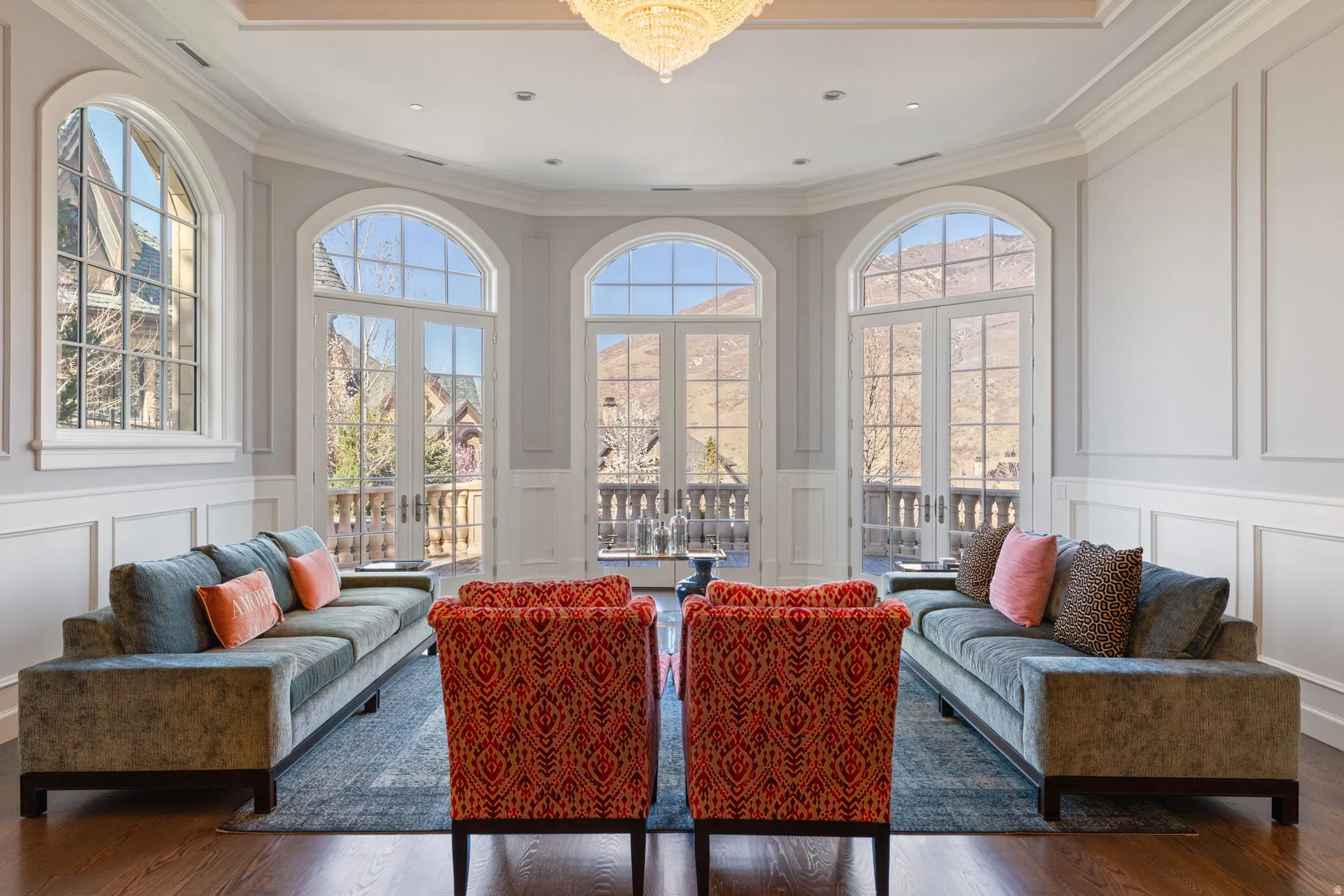 Living area featuring a decorative wall, ornamental molding, french doors, dark wood-style floors, and a chandelier