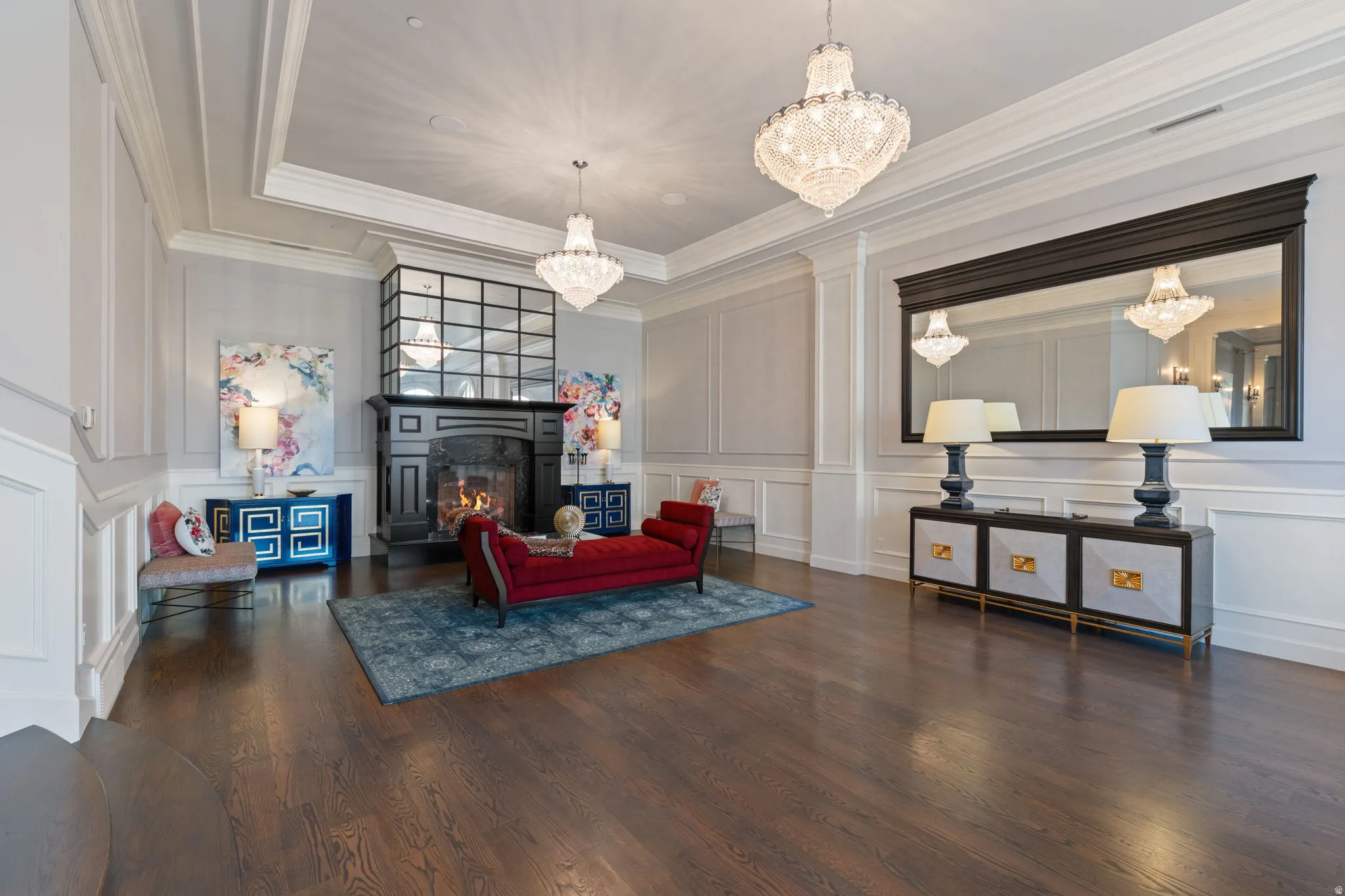 Living area featuring dark wood-style floors, a decorative wall, suspended lighting, and a fireplace